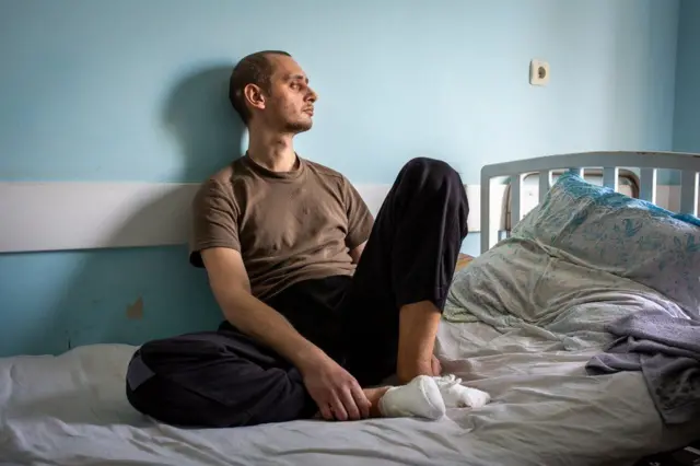 A man sits on a hospital bed