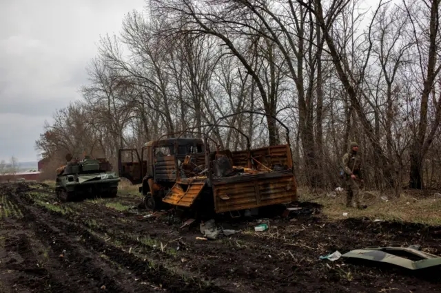 A Ukrainian soldier walks next to destroyed Russian military vehicles, one marked with the "Z" symbol earlier this month in the Kharkiv region