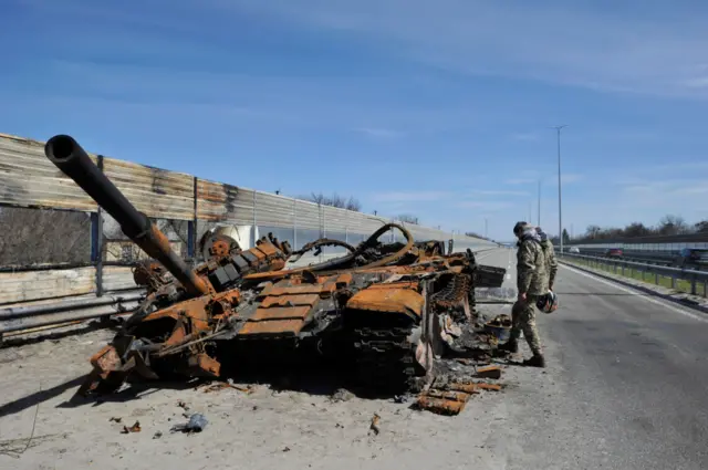 A man inspects destroyed tank of the Russian army to the west of Kyiv