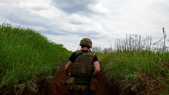 A Ukrainian serviceman walks in a trench in eastern Ukraine's Donetsk region