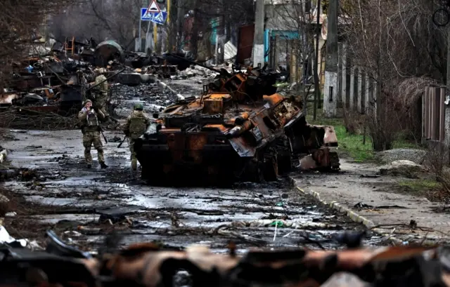 Image shows Ukrainian soldiers inspecting destroyed Russian tank