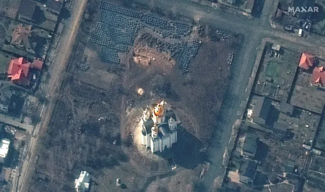 Maxar technologies says this satellite image shows a grave site with an approximately 45-foot (13.7 meters) long trench near the Church of St. Andrew and Pyervozvannoho All Saints, in Bucha, Ukraine