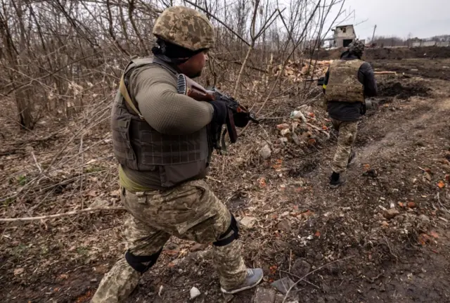 Ukrainian servicemen patrol in a trench at the front line east of Kharkiv on March 31, 2022.