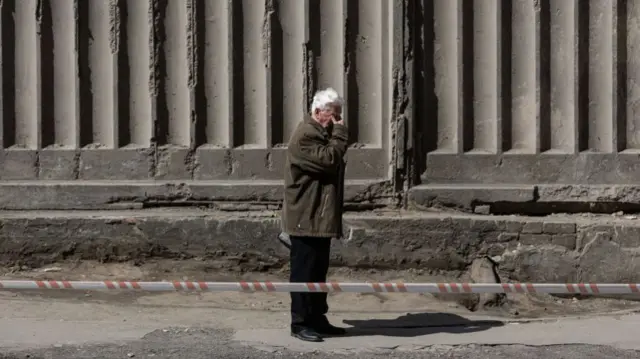 An elderly man cries after observing a heavily damaged apartment building, on April 30, 2022 in Kyiv