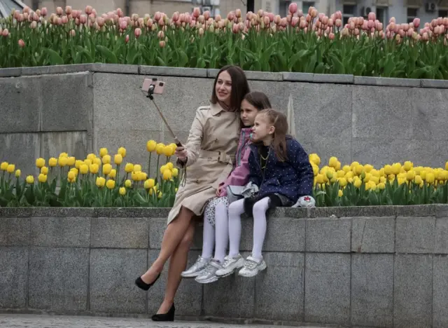 A woman takes a selfie with children near the blooming tulips, amid Russia"s invasion of Ukraine, in central Kyiv, Ukraine, April 30, 2022.