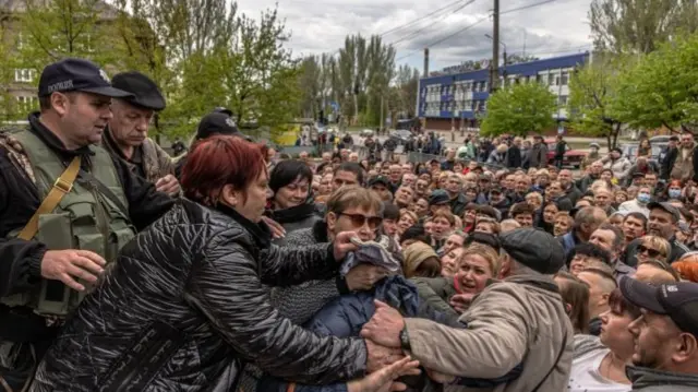 A group of people argue as they wait with other residents to receive humanitarian aid in Zaporizhzhia, Ukraine, 30 April 2022