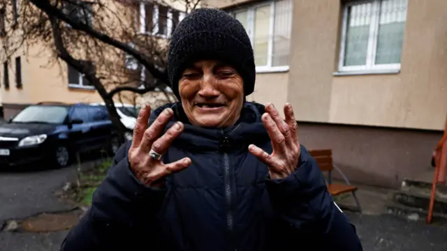 A woman bursting into tears outside a residential building in Bucha
