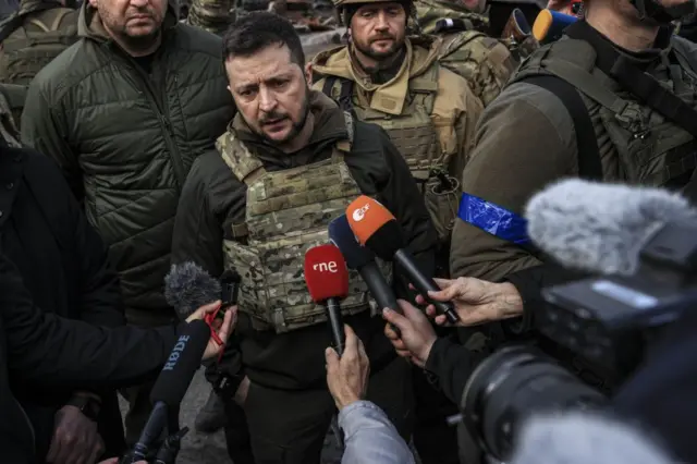 Volodymyr Zelensky talks to journalists while flanked by Ukrainian soldiers