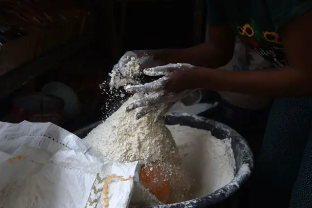 A vendor measures wheat flour in a cup for retail at a market in Ibafo, south-western Nigeria, in March 2022.