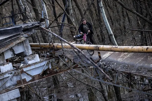 A man crosses a destroyed bridge near the village of Bohorodychne in the Donbas region on 5 April, 2022