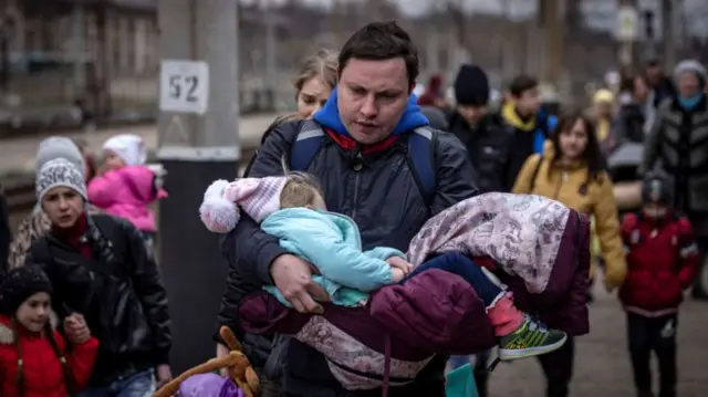 A man carries a little girl as families wait to board a train at Kramatorsk central station, 4 April