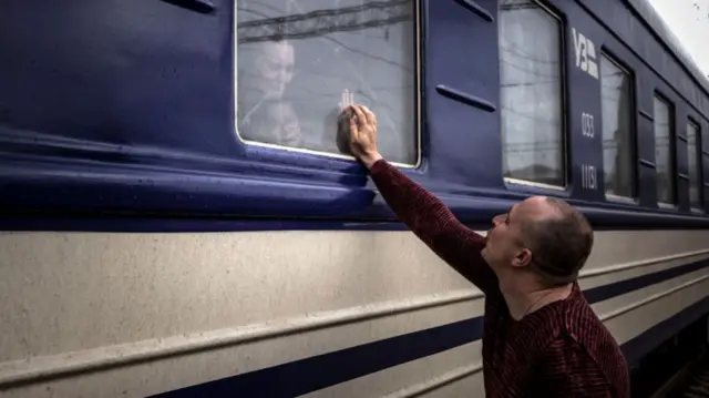 A man holds his hand up to the window of a train in Kramatorsk