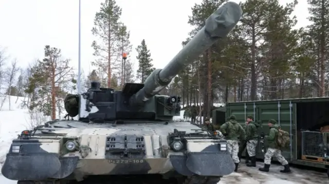 Finnish soldiers stand next to a tank during a military exercise called "Cold Response 2022"