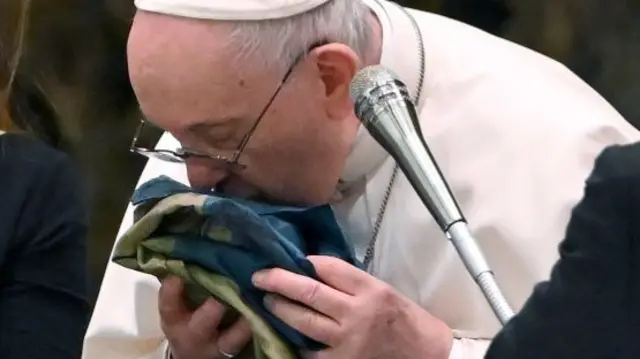 Pope Francis kissing Ukrainian flag sent to him from the town of Bucha