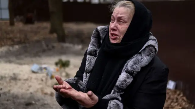 A Bucha women weeps at the grave of her son, who is now buried in her garden