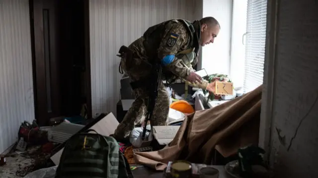 A Ukrainian soldier retrieves a wedding photo from his flat in the town of Hostomel, outside Kyiv