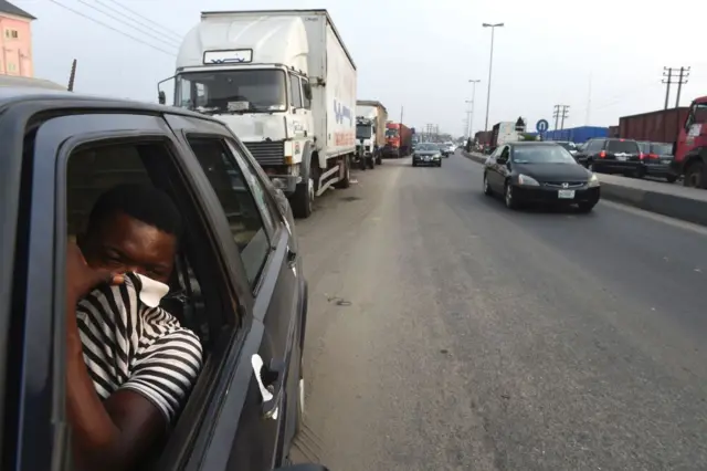 Man covering his nose in a car in Nigeria