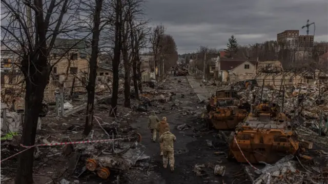 European Pressphoto Agency epa09874821 Members of the Ukrainian military walk past destroyed Russian military machinery on the street, in Bucha