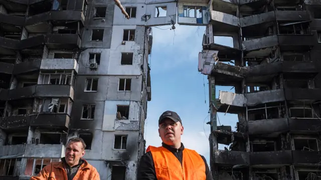 Clean-up workers stand in front of buildings destroyed by shelling in Borodyanka