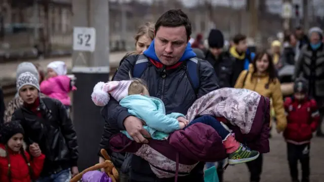 A man carries a little girl amid crowds at Kramatorsk station