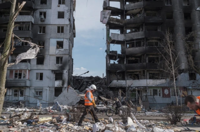 A rescuer walks past a row of shelled residential flats in Borodyanka