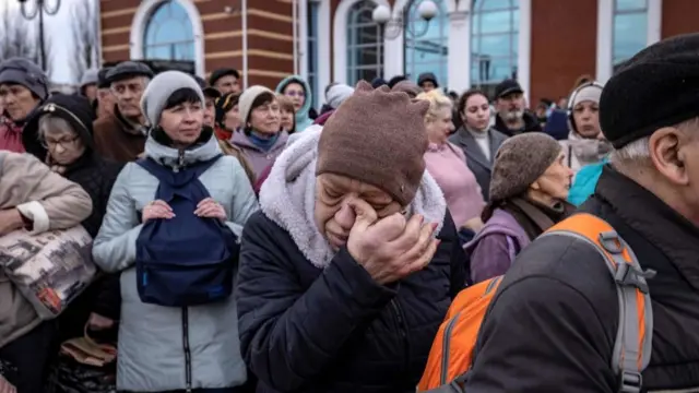 A woman wipes her eye as families wait to board a train at Kramatorsk central station