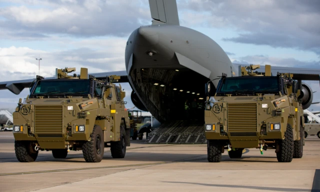 Two Bushmaster vehicles on the tarmac outside the Australian military aircraft