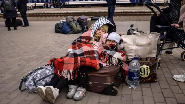 Children lay down on luggage on the station's platform