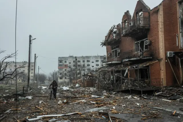 Man walks past building damaged by shelling in Makariv