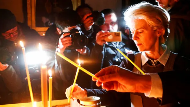 Ursula von der Leyen lights a candle in a church in Bucha