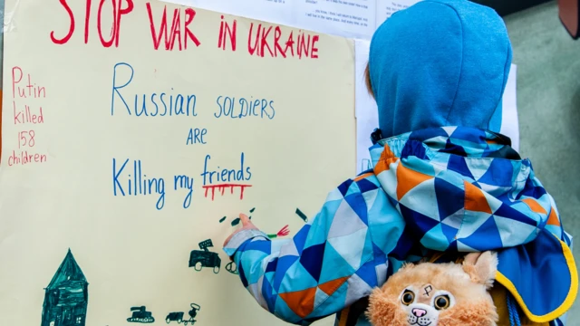 A boy reading messages against the war in Ukraine