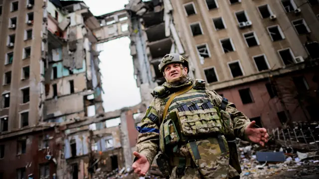 A soldier stands in front of a destroyed Ukrainian government building in Mykolaiv