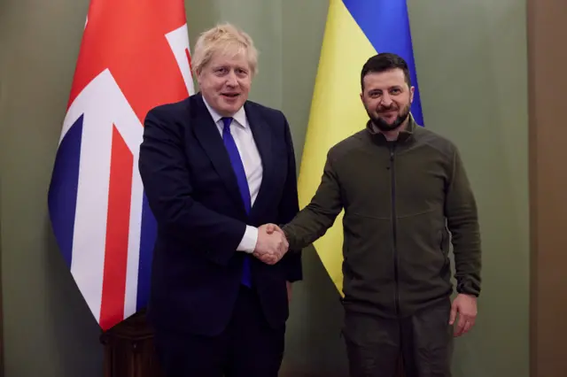 The British prime minister and Ukrainian president shake hands in front of their countries' flags