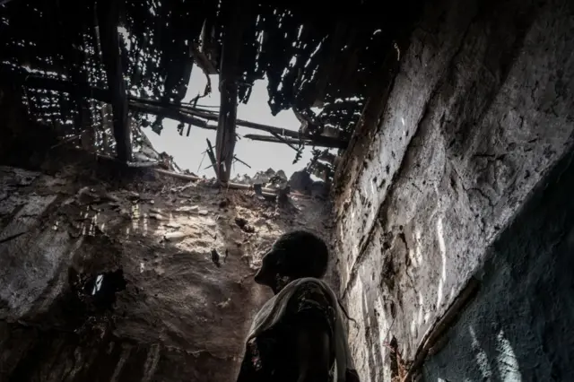 A woman inside a home destroyed during the civil war.