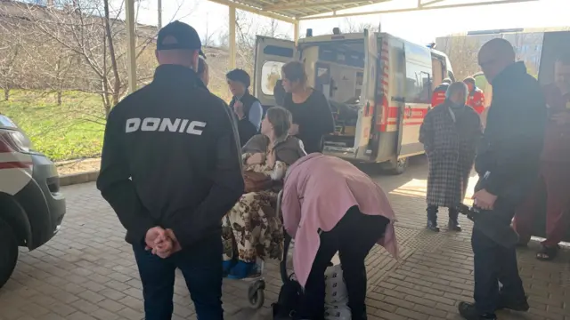 Anastasiya sits in a wheelchair close to an ambulance at Kramatorsk hospital