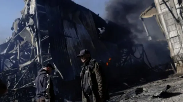 People walk at a damaged area inside a burning plant, following Russian shelling, Kharkiv, Ukraine 30 April