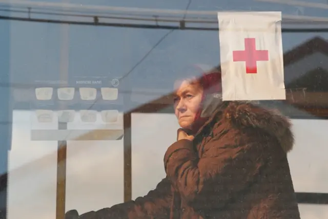 A woman is seen inside a bus before departing from a temporary accommodation centre