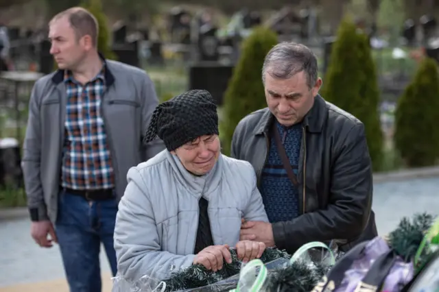 Anatolii and Olena, parents of a killed Ukrainian soldier Oleksandr Mozhaiko, grieve next to this grave on May 1, 2022 in Irpin, Ukraine