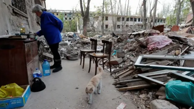 Resident cooking outside damaged buildings in Mariupol