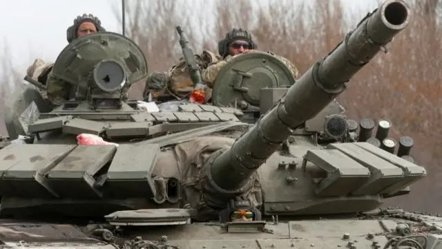 Service members of pro-Russian troops drive a tank during Ukraine-Russia conflict on a road outside the southern port city of Mariupol