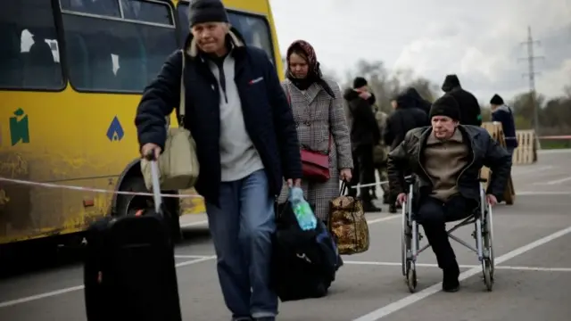 Ukrainian refugees from Mariupol area walk after arriving in a small convoy that crossed through a territory held by Russian forces