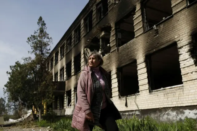 A resident walks past a damaged school in Ukraine's Kharkiv region