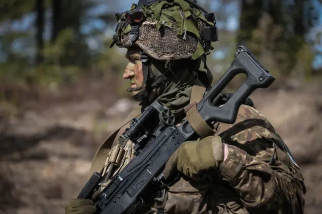 A Finnish soldier holsters a rifle during a training exercise