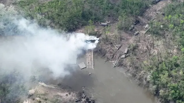 Smoke rises from a makeshift bridge across the Siverskyi Donets river