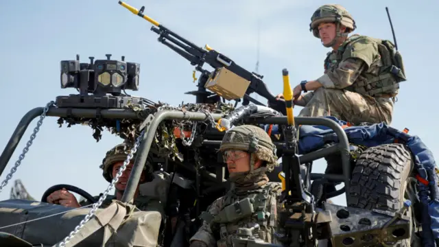 Three soldiers in a military vehicle with guns