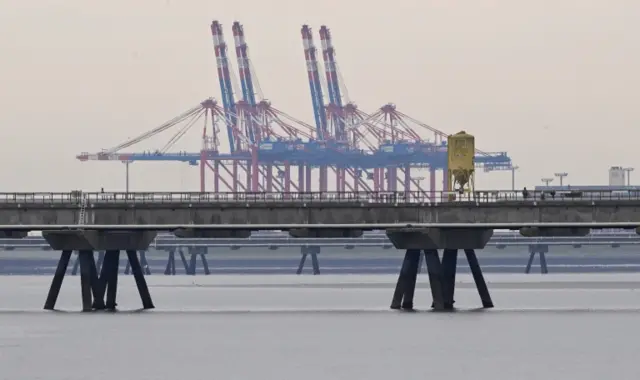 A pier for a planned floating LNG gas terminal is seen in front of a container terminal in the harbour in Wilhelmshaven, Germany. Photo: May 2022