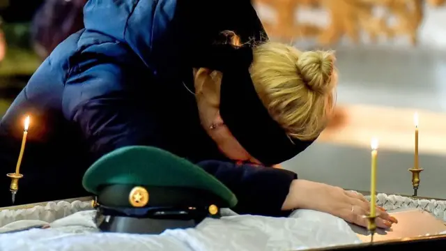 A woman leans over the coffin of a dead soldier