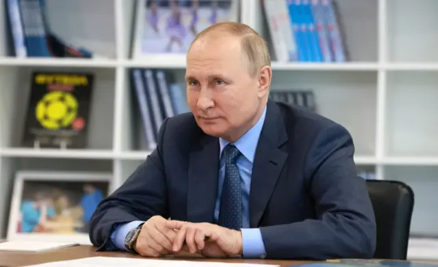 Vladimir Putin sits at a desk