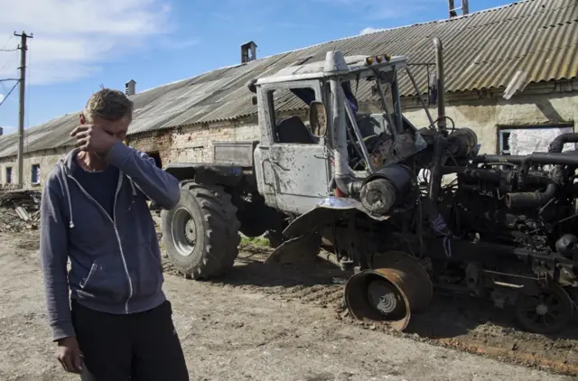 A local man reacts near his destroyed tractor on a farm in the village of Mala Rohan, near Kharkiv, Ukraine, 13 May 2022