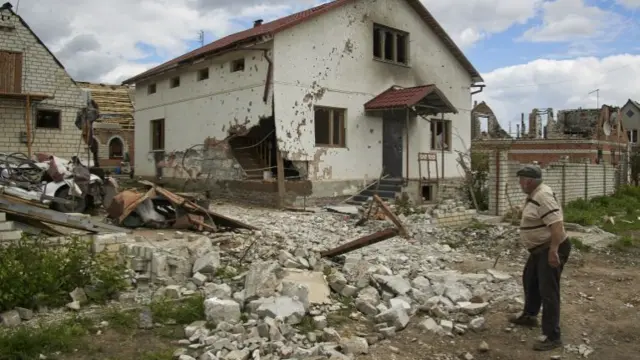 A resident walking near destroyed property in the area of Kharkiv